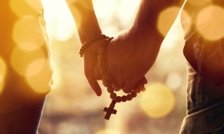 Hand in Hand mit Gebetskette mit Kreuz